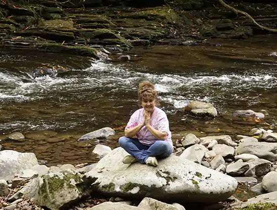Dr. Gwen Ford praying for her viewers on her favorite rock in Cherokee Park, NC