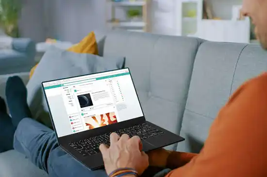 A man in orange sweater browsing social website on laptop